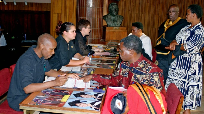 Photo of a table with sample images with cashiers left and clients to the right filling order forms.