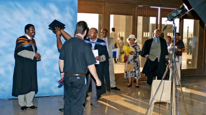 Photo of a photographer in front of a backdrop with a line of people at a temporary family studio.