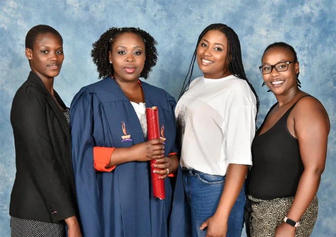 Half-length photo of an award recipient and guests standing in front of a blue backdrop.