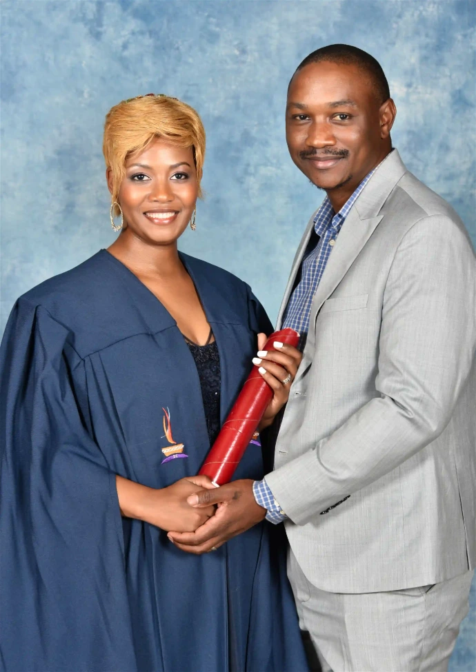 Half-length photo of an award recipient and her husband in front of a blue backdrop.