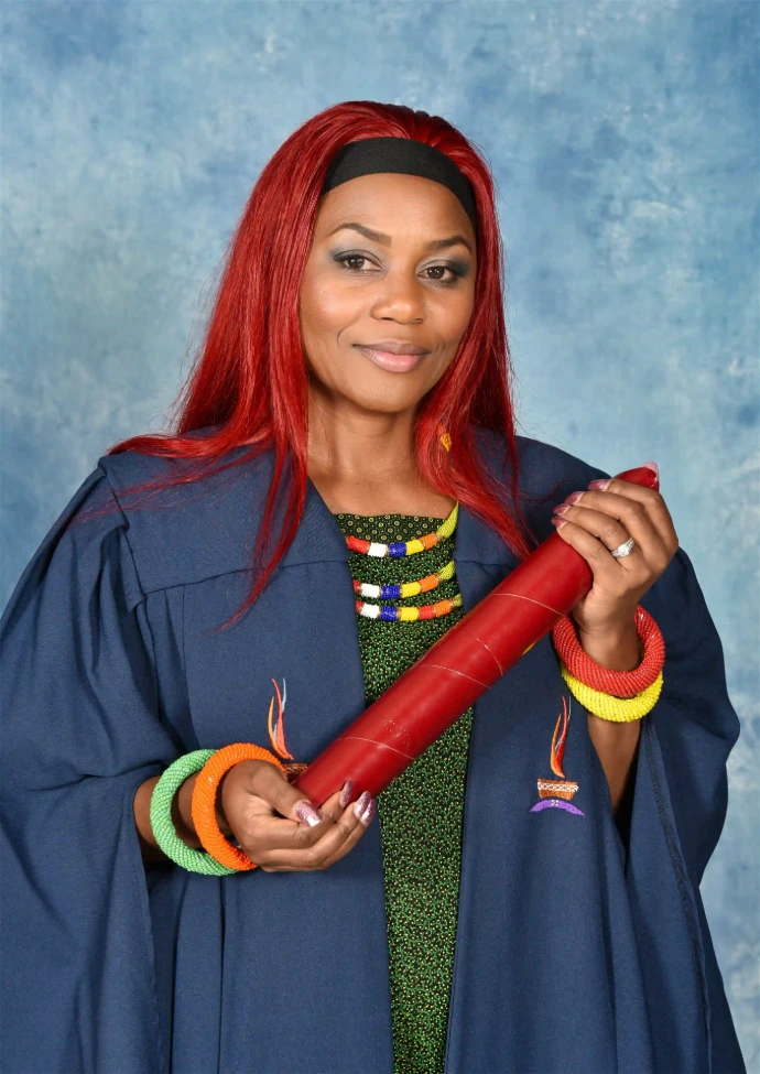 Half-length photo of an award recipient holding a scroll in front of a blue backdrop.