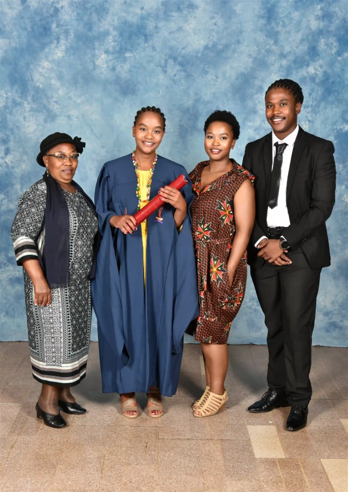 Full-length photo of an award recipient and guests standing in front of a blue backdrop.